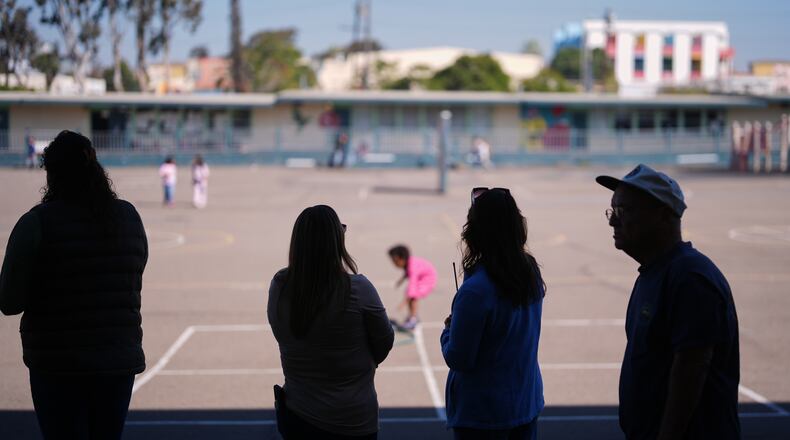 Teachers look on as students play on the playground at Perkins K-8 School Thursday, Nov. 13, 2025, in San Diego. (AP Photo/Gregory Bull)