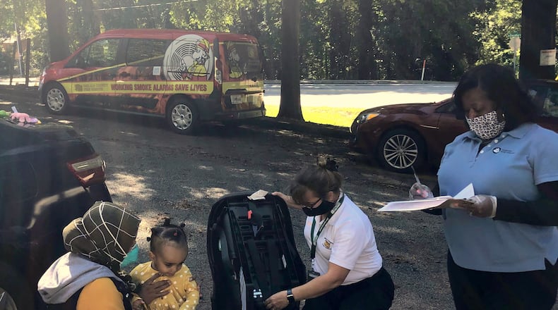 Scottdale Early Learning Parent Educator Tamra Davenport and a representative from Safe Kids DeKalb check car seats as part of SEL’s Parents as Teachers program. CONTRIBUTED