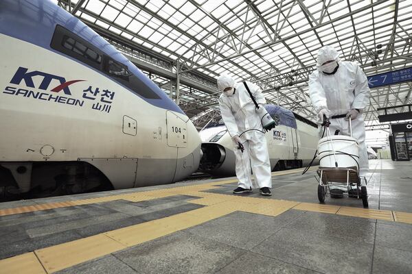 Workers wearing protective gears spray disinfectant as a precaution against the new coronavirus at Seoul Railway Station in Seoul, South Korea. (Jin Yeon-soo/Yonhap via AP)