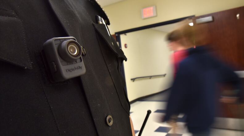 Officer Tate Ledford of the Cobb County School District Police Department, wearing a body camera, conducts a routine check at Wheeler High School in Marietta. Clayton, Cobb and Gwinnett Counties are among the school districts whose officers wear the cameras. Officers in Atlanta, DeKalb and Fulton do not. DeKalb is looking into buying cameras for its officers, a spokesman says. HYOSUB SHIN / HSHIN@AJC.COM