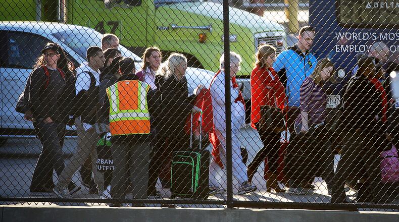 Passengers leave a fire station as they board a shuttle taking them off the tarmac at Hartsfield-Jackson Atlanta International Airport where two airplanes were being searched after authorities received what they described as credible bomb threats, Saturday, Jan. 24, 2015, in Atlanta. (AP Photo/David Goldman)
