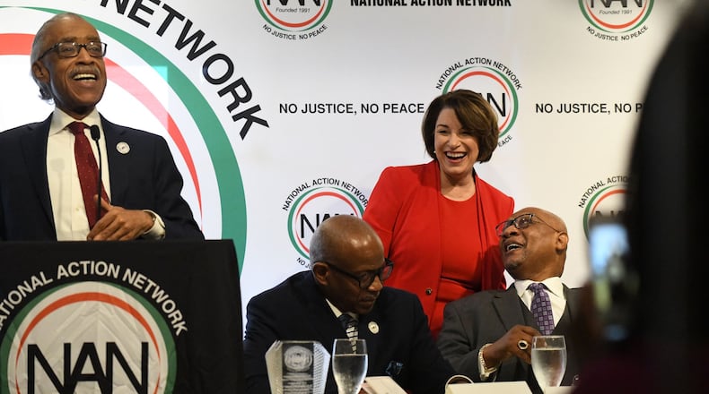 U.S. Sen. Amy Klobuchar of Minnesota laughs as the Rev. Al Sharpton tells the crowd at Paschal’s Restaurant that she once raised $17,000 from her ex-boyfriends. In all, five of the candidates who participated in Wednesday night’s Democratic presidential debate attended Thursday’s gathering put on by Sharpton’s National Action Network. Candidates made stops across the city on Thursday, many of them aiming to appeal to black voters. PHOTO BY ELISSA BENZIE