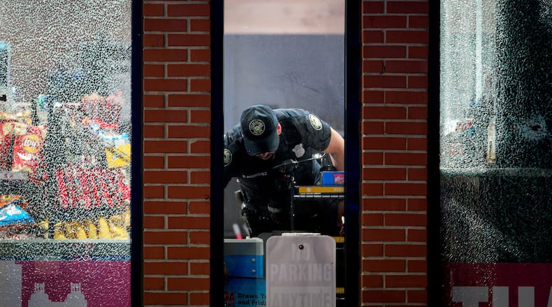 An Atlanta police officer searches for evidence inside a Shell gas station on Northside Drive on Sunday, July 24, 2022, after several people were injured in an apparent drive-by shooting. (Photo: Ben Hendren for The Atlanta Journal-Constitution)