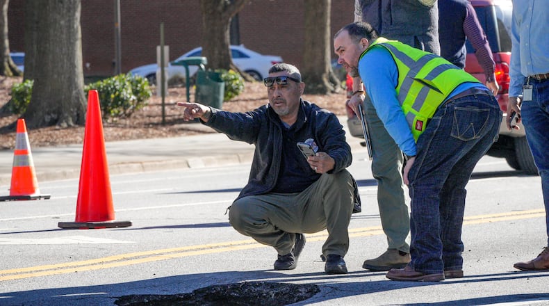 An Atlanta Watershed employee (left) speaks with workers from Coca-Cola headquarters after a large hole opened up on North Avenue on Tuesday.