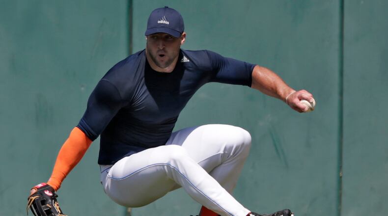 Former NFL quarterback Tim Tebow loses his footing as he fields a ball during outfield drills at USC's Dedeaux Field in Los Angeles during a private baseball tryout. (Robert Gauthier / Los Angeles Times)