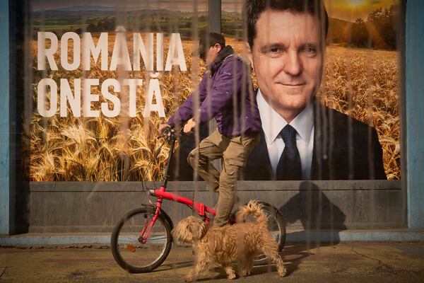 A man and a dog pass by posters of Nicusor Dan, the mayor of Bucharest and presidential candidate in the upcoming May elections in Bucharest, Romania, Friday, March 28, 2025. (AP Photo/Vadim Ghirda)