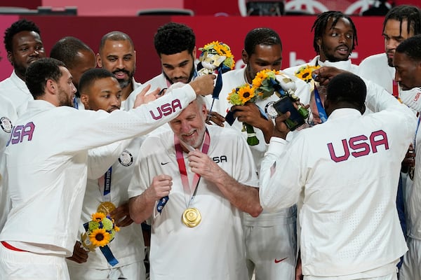 FILE - United States players put a gold medal on head coach Gregg Popovich during the men's basketball medal ceremony at the 2020 Summer Olympics, Saturday, Aug. 7, 2021, in Tokyo, Japan. (AP Photo/Charlie Neibergall, File)