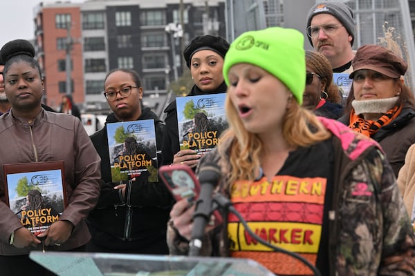 Supporters hold pamphlets as Katie Giede, Waffle House employee and union member, speaks to members of the press during an event to launch its policy platform outlining community-driven demands ahead of the 2026 FIFA World Cup on the Steele Bridge near the Mercedes-Benz Stadium, Thursday, December 4, 2025, in Atlanta. (Hyosub Shin/AJC)