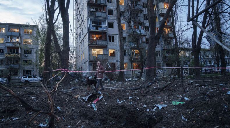 A woman with a dog walks among the rubble of a house damaged after a Russian strike on residential area in Kyiv, Ukraine, on Thursday, April 16, 2026. (AP Photo/Evgeniy Maloletka)