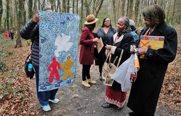Juandamarie Gikandi (left) shows a replica of a Harriet Powers quilt to Jan Hollins (far right). Roughly 150 years after Powers stitched biblical stories and lived experiences into fabric, her quilts now hang in the Smithsonian Institution and the Museum of Fine Arts, Boston. (Nell Carroll for the AJC 2023)