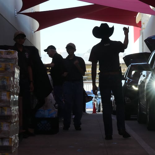 Aidan Tavor, center, directs traffic as volunteers help load vehicles during a food distribution at the San Antonio Food Bank for SNAP recipients and other households affected by the federal shutdown, Thursday, Nov. 6, 2025, in San Antonio. (AP Photo/Eric Gay)