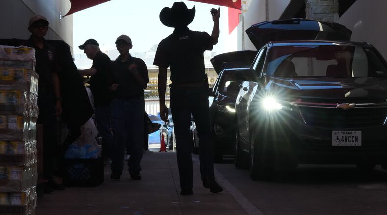 Aidan Tavor, center, directs traffic as volunteers help load vehicles during a food distribution at the San Antonio Food Bank for SNAP recipients and other households affected by the federal shutdown, Thursday, Nov. 6, 2025, in San Antonio. (AP Photo/Eric Gay)