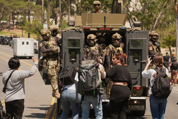 Federal agents ride on and armored vehicle at MacArthur Park Monday, July 7, 2025, in Los Angeles. (AP Photo/Damian Dovarganes)