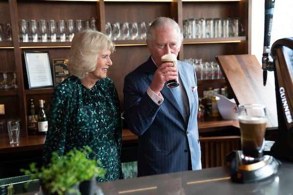 FILE _ Britain's Prince Charles is flanked by Camilla, Duchess of Cornwall, as he tastes a pint of Guinness during a visit to the Irish Cultural Centre in west London, to celebrate its 25th anniversary in the run-up to St Patrick's Day, Tuesday, March 15, 2022. (Arthur Edwards, Pool via AP, File)