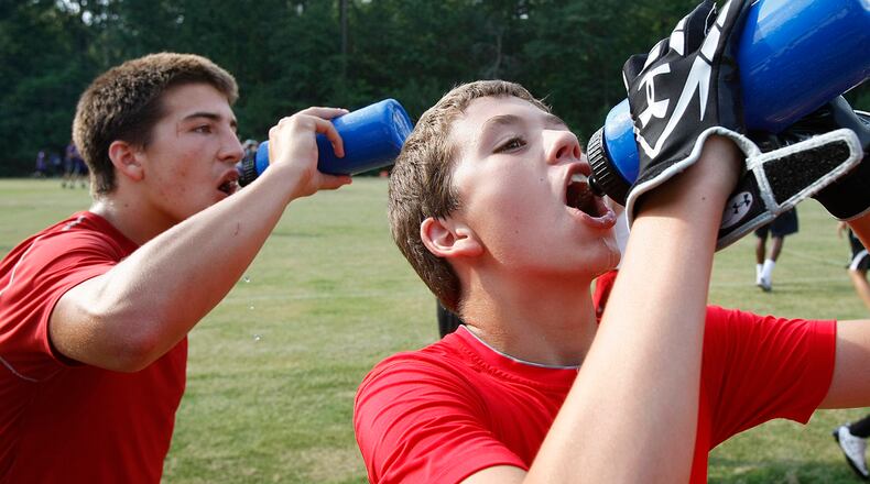 These North Gwinnett football players took in plenty of fluids during a water break at a 7-on-7 football camp at Duluth High School in this 2010 AJC file photo. It's one way that high school sports programs work to keep players from suffering heat-related illness, which can be fatal. A study out of Georgia Tech looks at ways to cut heat-related deaths by more than half.