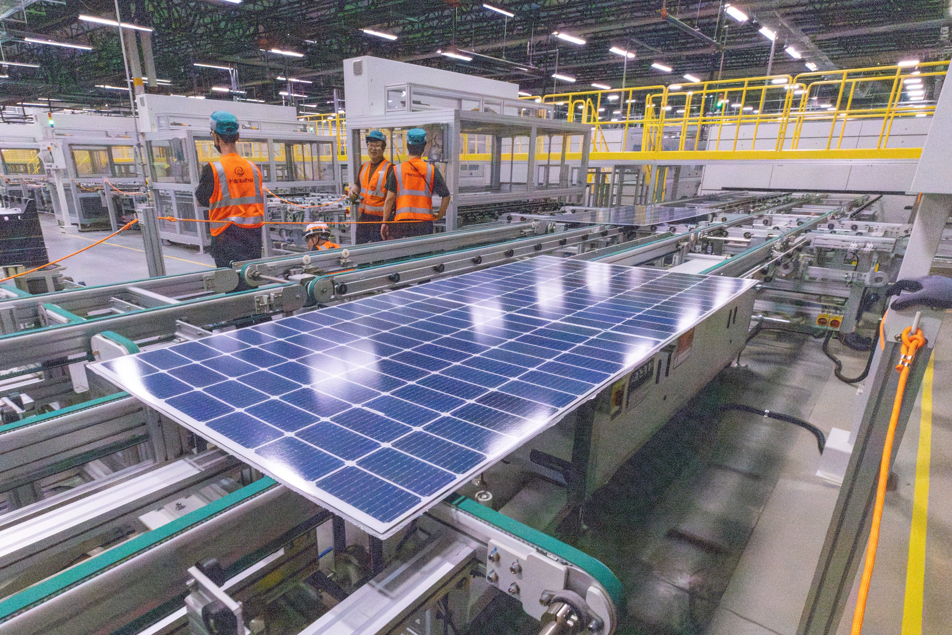Workers keep an eye on solar panels as they move through the automated assembly line at the Qcells module production facility in Cartersville, 2024. (Steve Schaefer/AJC)