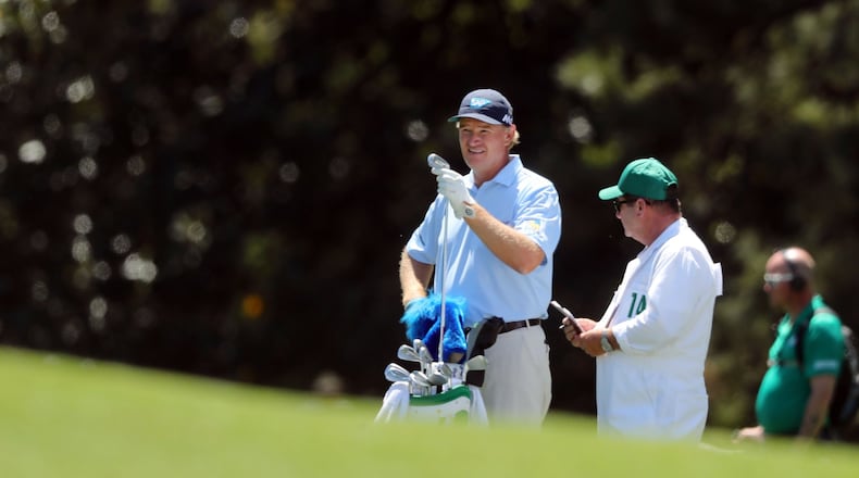 Ernie Els and his caddie, Ricci Roberts, await his shot on the 18th fairway. Els shot a 78 as the first player off the tee on Sunday. CURTIS COMPTON/ AJC