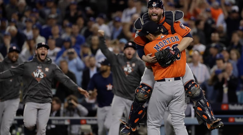 Houston Astros catcher Brian McCann leaps in the arms of starting pitcher Charlie Morton after Game 7 of baseball's World Series against the Los Angeles Dodgers Wednesday, Nov. 1, 2017, in Los Angeles. The Astros won 5-1 to win the series 4-3.