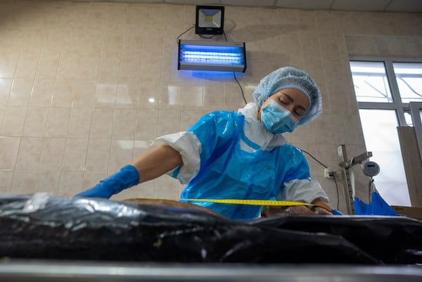 A forensic worker in Kyiv, Ukraine, examines the body of a prisoner of war repatriated by Russia, June 24, 2024. (AP Photo/Alex Babenko)