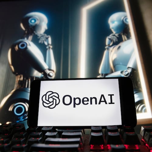 The OpenAI logo is displayed on a cellphone with an image on a computer monitor generated by ChatGPT's Dall-E text-to-image model, Dec. 8, 2023, in Boston. (Michael Dwyer/AP File)