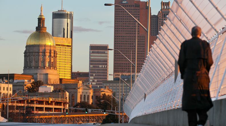 GOLDEN SUNRISE-- A pedestrian walks along Capitol Avenue at I-20 as a sunrise brought its golden rays across the Atlanta skyline in March, 2013. JOHN SPINK / JSPINK@AJC.COM