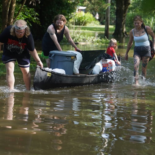 Scott Conrad, left, Joseph Workman, second from left, Ronan Carey, in the boat, and Kesley Patterson use a kayak to transport items from their flooded homes in Indianapolis, Sunday, Aug. 16, 2026. (AP Photo/Obed Lamy)
