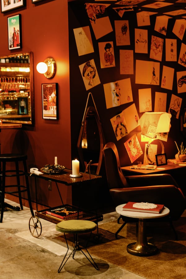 Y Bar's interior shows a wall papered with drawings by director Federico Fellini a little table and rolling cart sit next to the wall.
