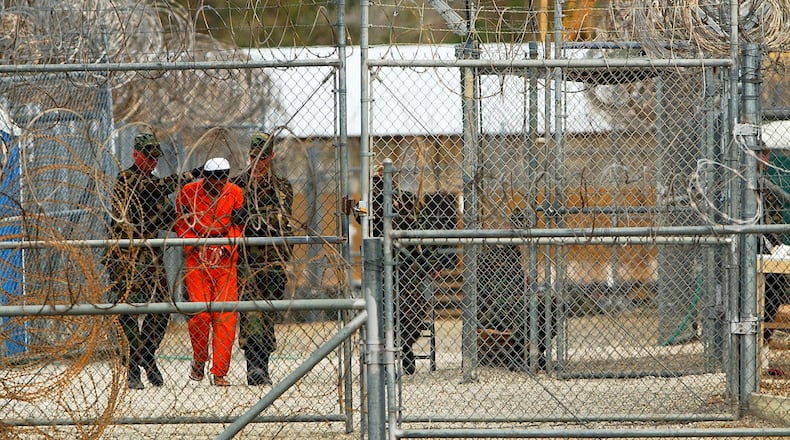 Marines transport a detainee behind layers of fencing and razorwire in Camp X-Ray February 6, 2002 in Guantanamo Bay, Cuba. (Photo by Chris Hondros/Getty Images)