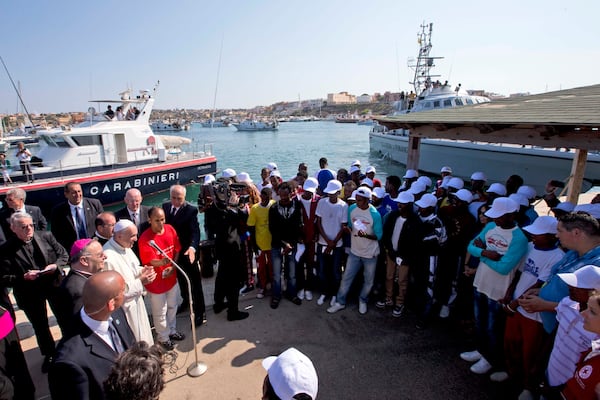 FILE - Pope Francis, left, speaks to migrants, wearing white caps, during his visit to the island of Lampedusa, southern Italy, Monday July 8, 2013. (AP Photo/Alessandra Tarantino, Pool, File)