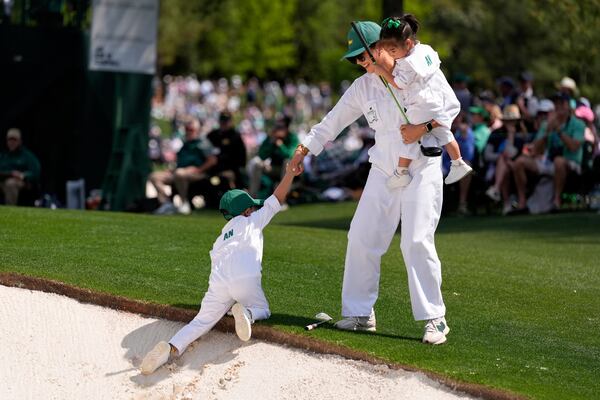 Byeong Hun An's, of South Korea, wife, Melissa, helps her son Sun-woo, 5, out of the bunker on the first hole as she holds daughter Ji-Woo, 2, during the par-3 contest at the Masters golf tournament, Wednesday, April 9, 2025, in Augusta, Ga. (AP Photo/Ashley Landis)