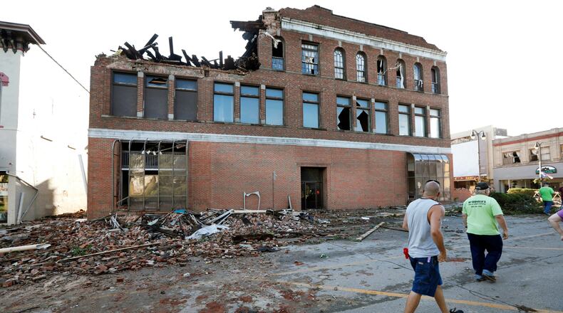 Local residents walk past a tornado-damaged building on Main Street, Thursday, July 19, 2018, in Marshalltown, Iowa. Several buildings were damaged by a tornado in the main business district in town including the historic courthouse. (AP Photo/Charlie Neibergall)