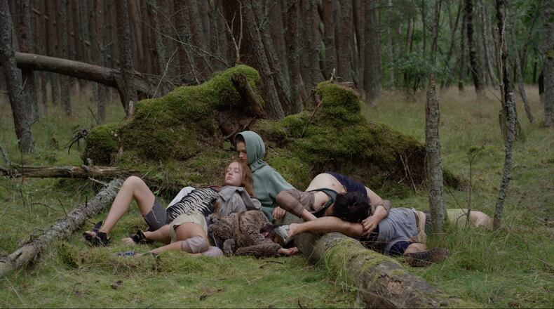 Dancers rest against the mossy surfaces of a dark forest in the dance film "Songs from the Compost," on view at the Michael C. Carlos Museum through May 19.