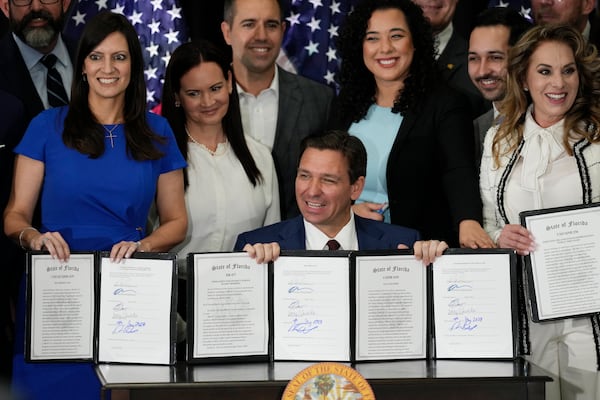 FILE - Florida Governor Ron DeSantis, seated, and other elected, state, and local officials pose with a group of education-related bills after DeSantis signed them into law at a press conference in Miami, Tuesday, May 9, 2023. (AP Photo/Rebecca Blackwell, File)