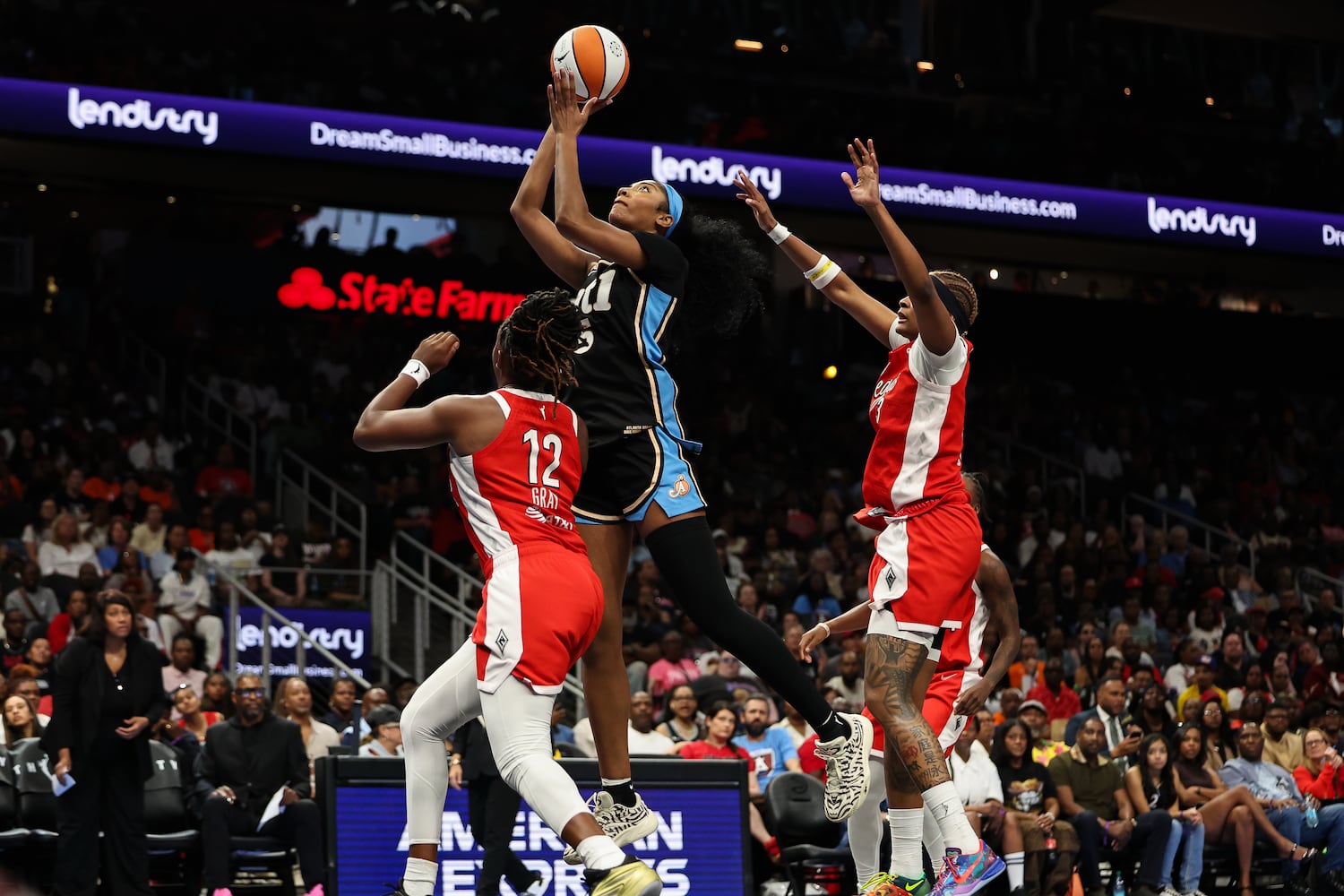 Dream forward Angel Reese (center) shoots against Aces guard Chelsea Gray (left) and forward NaLyssa Smith during the first half Sunday, May 17, 2026, at State Farm Arena in Atlanta. (Colin Hubbard for the AJC) 