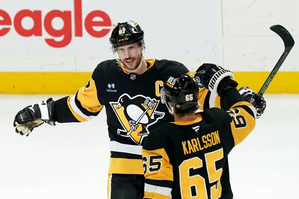 Pittsburgh Penguins' Sidney Crosby (87) celebrates with Erik Karlsson (65) after getting the winning goal during the overtime period of an NHL hockey game against the Ottawa Senators, Sunday, March 30, 2025, in Pittsburgh. (AP Photo/Matt Freed)
