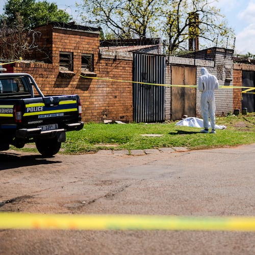 A forensic officer works at the scene where a sixth body, believed to be that of a woman, was found along a road in KwaThema, Springs, South Africa, Tuesday, Sept. 15, 2026. (AP Photo)