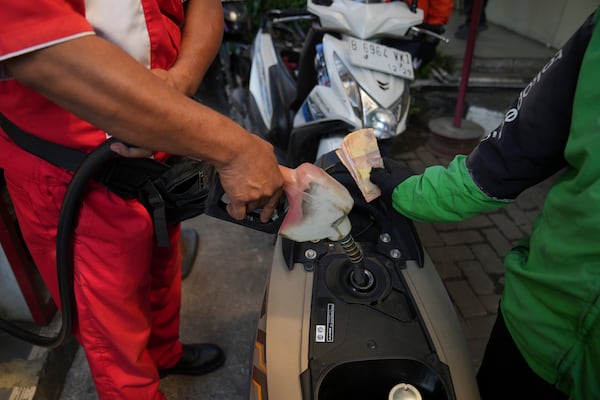 An employee fills up the tank of a customer's motorbike at a gas station in Jakarta, Indonesia, Monday, May 5, 2025. (AP Photo/Tatan Syuflana)