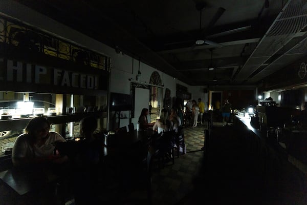 Customers sit inside a restaurant lit by battery-powered lanterns during an island-wide power outage, in Old San Juan, Puerto Rico, Wednesday, April 16, 2025. (AP Photo/Alejandro Granadillo)