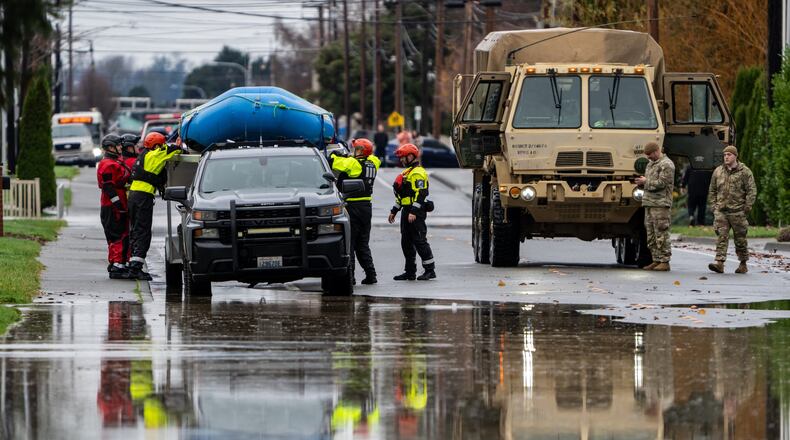 Emergency crews, including National Guard soldiers, wort in a neighborhood flooded by the Skagit River on Friday, Dec. 12, 2025, in Burlington, Wash. (AP Photo/Stephen Brashear)
