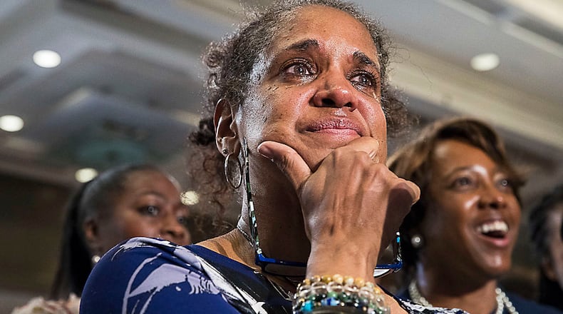 Nina Williams (center) becomes emotional as 'Lift Every Voice and Sing' also referred to as the 'Black National Anthem' is performed during the Stacey Abrams election night watch party in 2018. (Alyssa Pointer/AJC 2018 file)