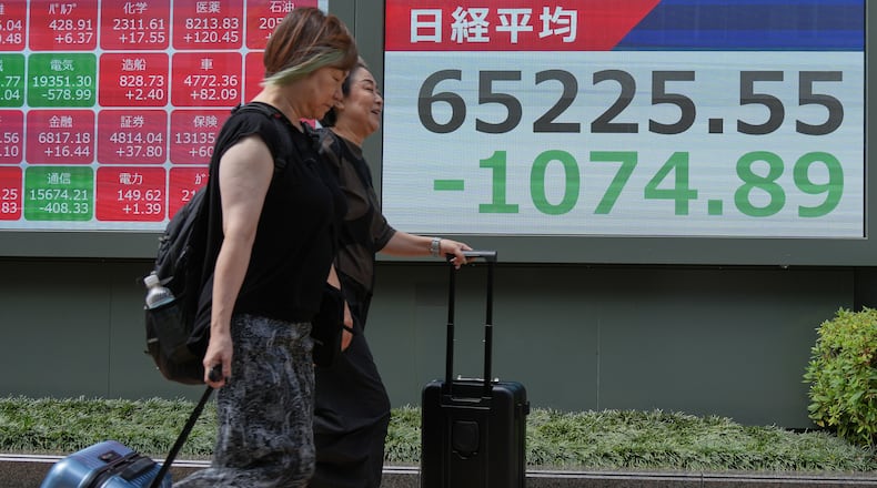 People walk past an electronic board showing Japan's Nikkei index at a securities firm Thursday, Aug. 6, 2026, in Tokyo. (AP Photo/Eugene Hoshiko)