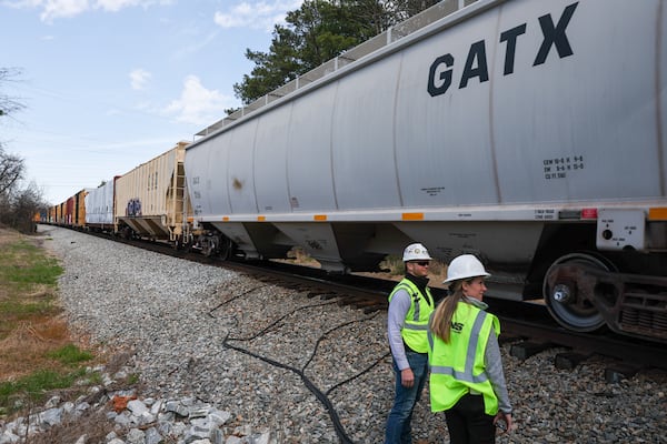 John Fleps (left), vice president for safety at Norfolk Southern, and Heather Garcia, senior communications manager, watch a train pass in Jackson during a tour for AJC reporters on March 7. Arvin Temkar/AJC