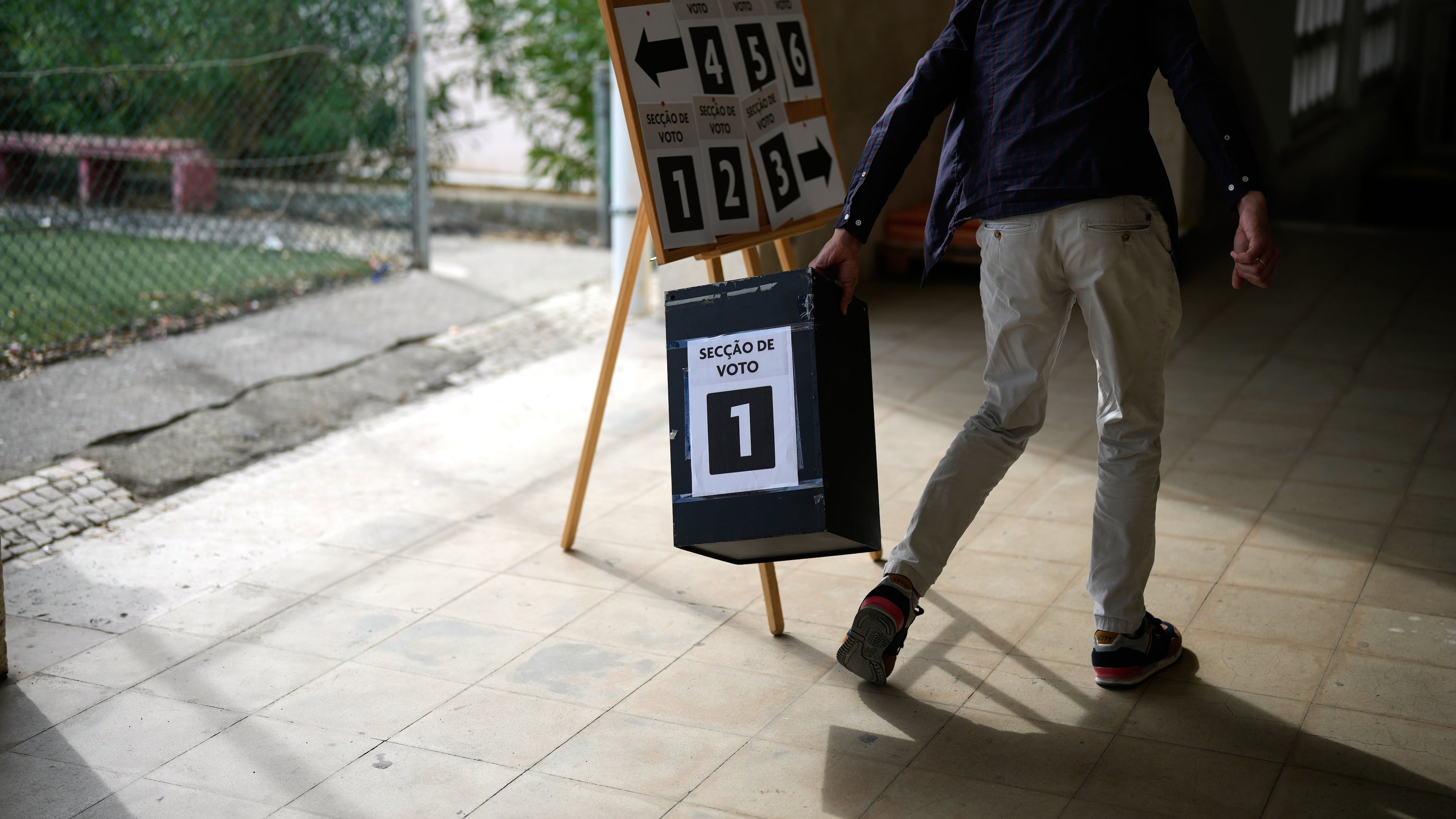 A worker picks up an empty ballot box at a polling station for Portugal's municipal elections in Lisbon, Sunday, Oct. 12, 2025. (AP Photo/Armando Franca)