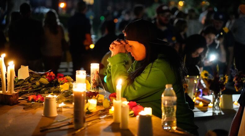 A woman prays during a candlelight vigil Tuesday, Aug. 4, 2026, in Twin Falls, Idaho, to honor the victims of a recent shooting at a local In-N-Out Burger. (AP Photo/Andrew Eakin)