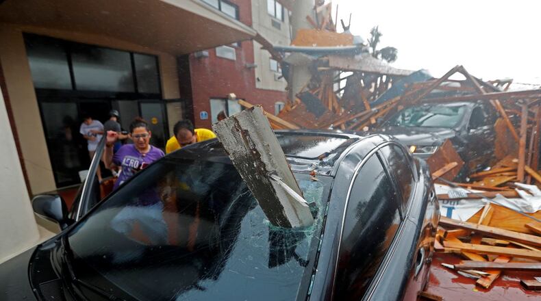 A woman checks on her vehicle as Hurricane Michael passes through, after the hotel canopy had just collapsed, in Panama City Beach, Fla., Wednesday. (AP Photo/Gerald Herbert)