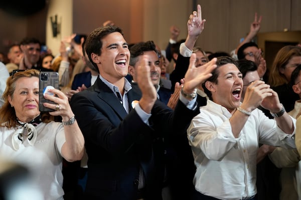Supporters of the center-right ruling coalition of Prime Minister Luis Montenegro react to exit polls following Portugal's general election, in Lisbon, Sunday, May 18, 2025. (AP Photo/Armando Franca)