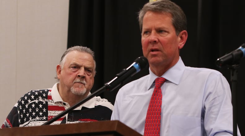 Cobb County Sheriff Neil Warren (left) looks on while Georgia Gov.r Brian Kemp (right) addresses the crowd during the 30th annual Cobb Sheriff's Corn Boilin' at Jim Miller Park in Marietta on Monday. Christina Matacotta/Christina.Matacotta@ajc.com