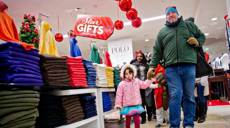 Ken Feinberg (right) holds his daughter Anauka's hand as they walk through Macy's at Lenox Square mall in Atlanta after doors opened for a previous Black Friday. JONATHAN PHILLIPS / SPECIAL