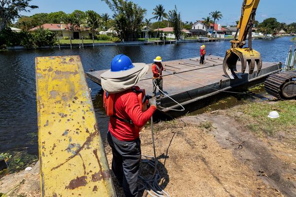 Workers with Arbor Tree and Land in West Palm Beach, secure a barge on the C-15 canal in Delray Beach, Florida, May 8, 2018. The SFWMD will be clearing banks of trees and brush along the canal to prevent flooding during the hurricane season. (Greg Lovett / The Palm Beach Post)