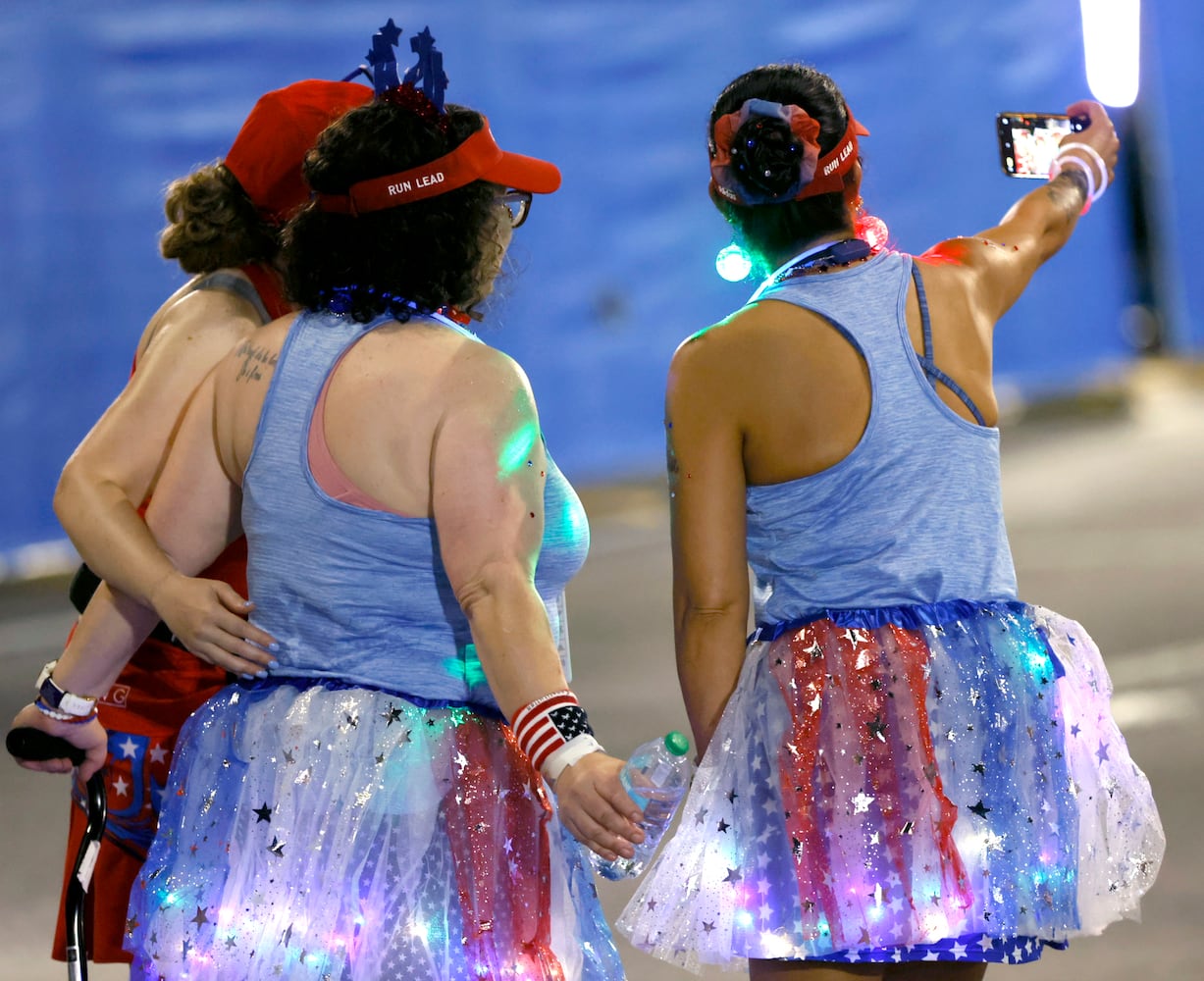 Early arrivals to the start of the 55th running of the Atlanta Journal-Constitution Peachtree Road Race take selfies in Atlanta on Thursday, July 4, 2024.   (Arvin.Temkar / ajc.com)